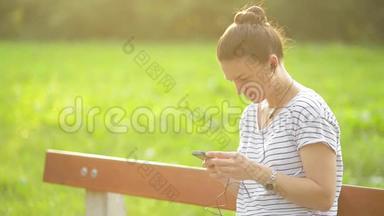 在公园里，一个带着耳机听着智能<strong>手机音乐</strong>的女人，一个使用智能手机的漂亮女人